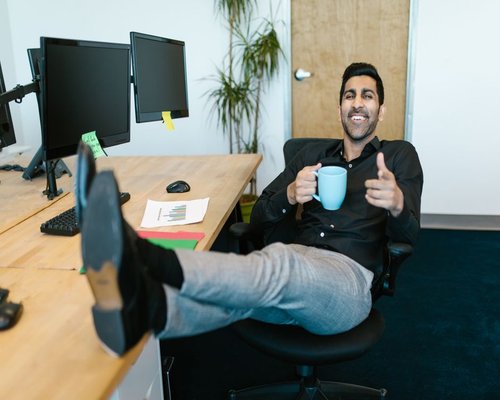 Person resting and drinking water at a modern desk setup