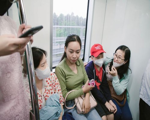 Commuters sitting closely together looking at smartphones on a train