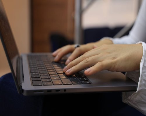 A close up of hands typing continuously on a laptop keyboard